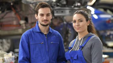 Weiblicher und männlicher Lehrling in Autowerkstatt